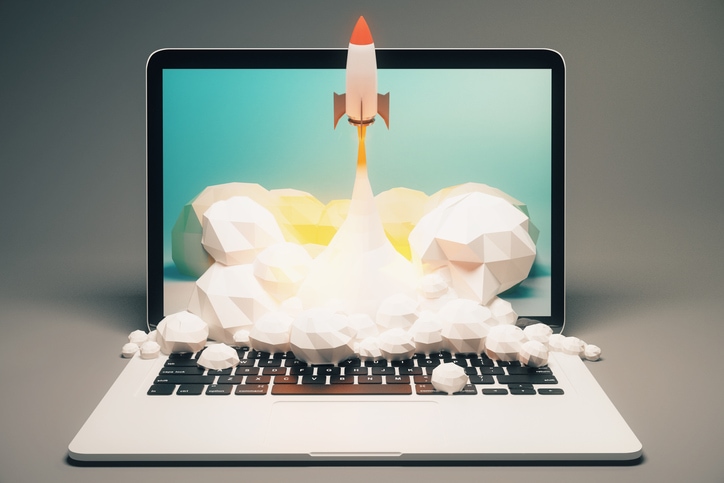 Startup concept with rocket flying out of laptop screen on grey background.