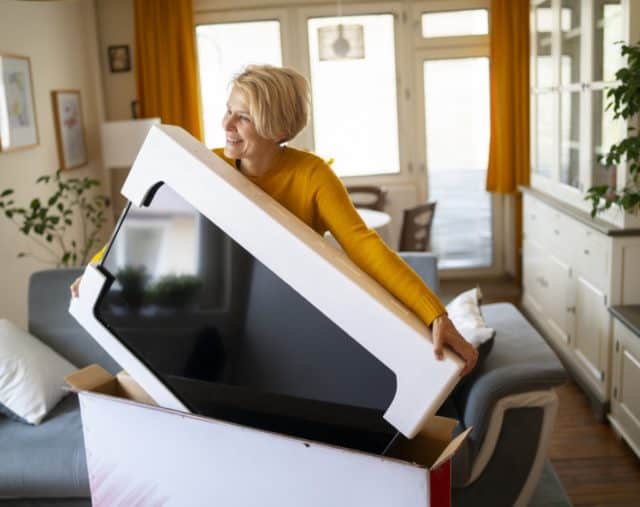consumer electronics analytics; woman pulling a tv out of its original packaging