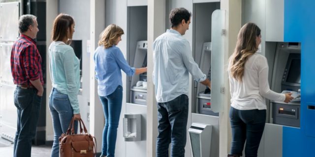 Banking customers line up to use ATMs.