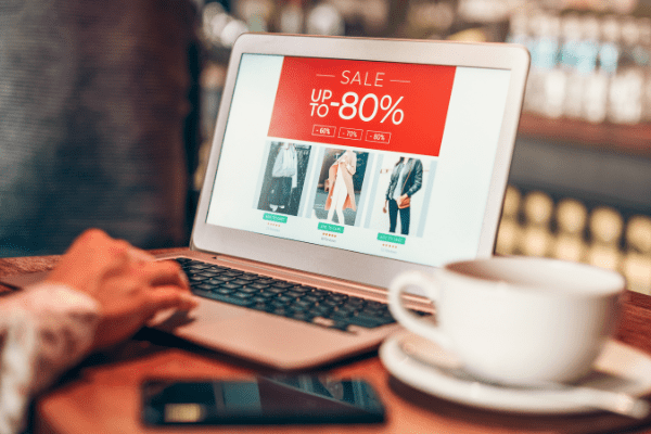 A customer on a laptop at a coffee shot is exposed to retail media advertising, which is produced to attract them into buying items.