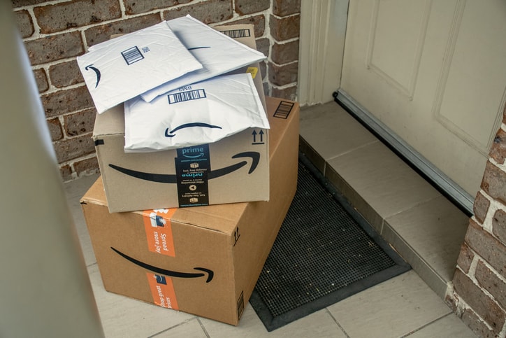 Amazon prime boxes and envelopes delivered to a front door of residential building.