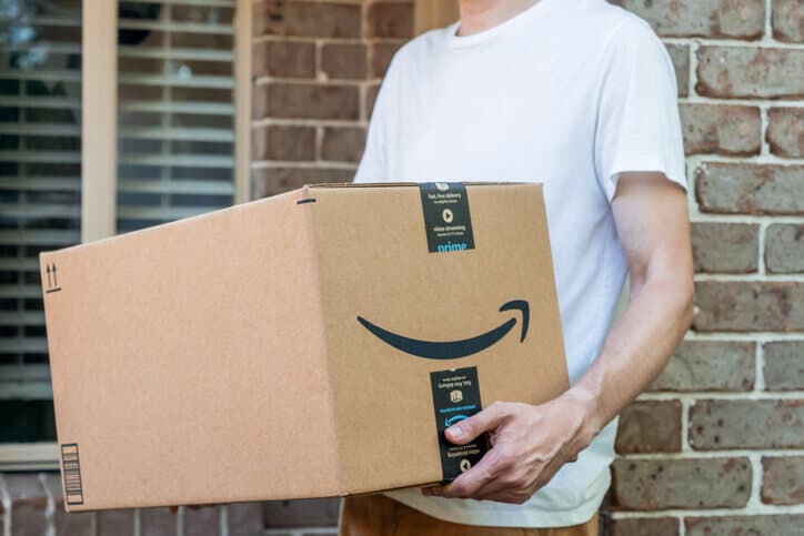 Person in a tee shirt holds an Amazon delivery box
