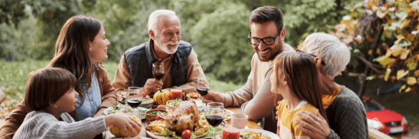 Several generations of people sit down at a table for a family reunion.