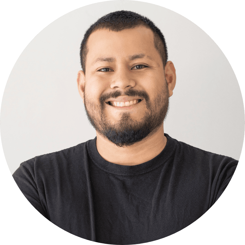 A man with short black hair and a beard, wearing a black t-shirt, smiles at the camera against a plain light background—perfect for a Paid Search and Paid Social case study profile image.
