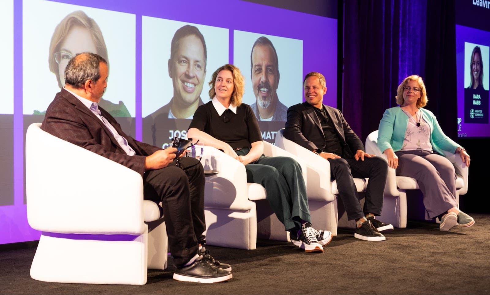 Vier Personen sitzen auf der Bühne auf weißen Stühlen und nehmen an einer Podiumsdiskussion zum Thema Social Commerce und Retail Media teil. Hinter ihnen werden Porträts und Namen auf einer großen Leinwand gezeigt. Die Kulisse wirkt wie bei einer Fachkonferenz oder einer Veranstaltung.