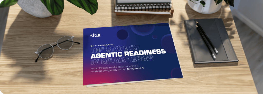 Ein Bericht mit dem Titel „The State of Agentic Readiness in Media Teams“ liegt auf einem Holztisch neben einer Brille, einer Pflanze, einem Notizblock und zwei Bleistiften. Der Bericht hat einen blau-lila Einband mit modernen grafischen Elementen.