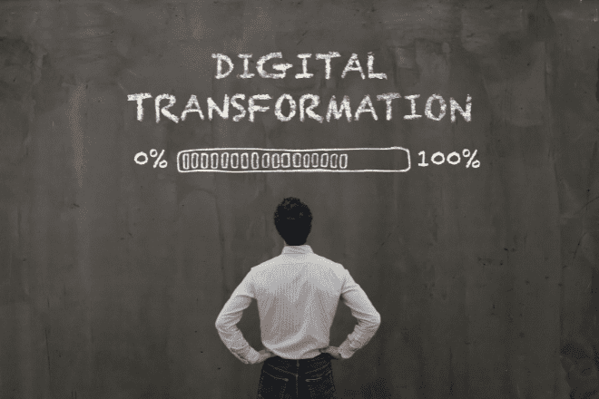 Une personne se tient face à un tableau noir sur lequel est inscrit « TRANSFORMATION NUMÉRIQUE », au-dessus d'une barre de chargement indiquant 0 % à 100 %, soulignant ainsi l'importance des stratégies omnicanales pour favoriser le progrès et une intégration fluide entre toutes les plateformes.