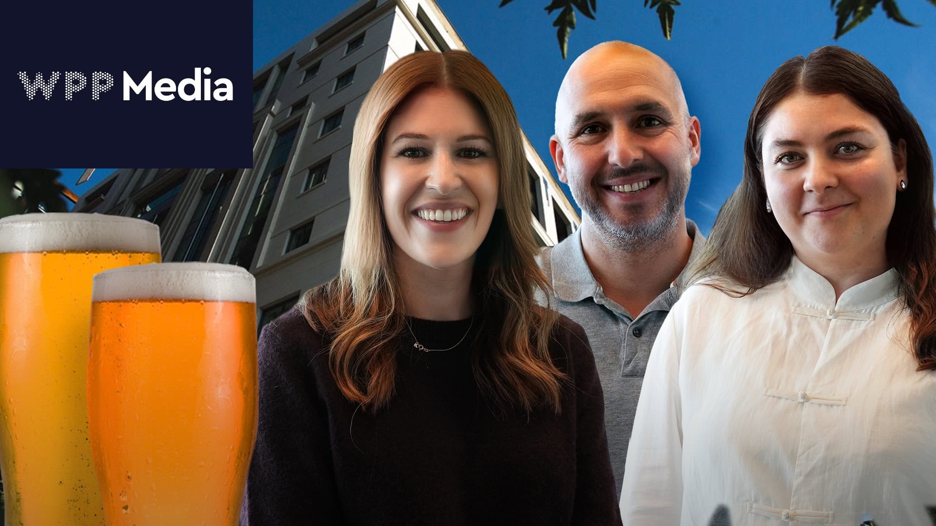 Three smiling people pose in front of a building with a WPP Media logo and two glasses of beer in the foreground.