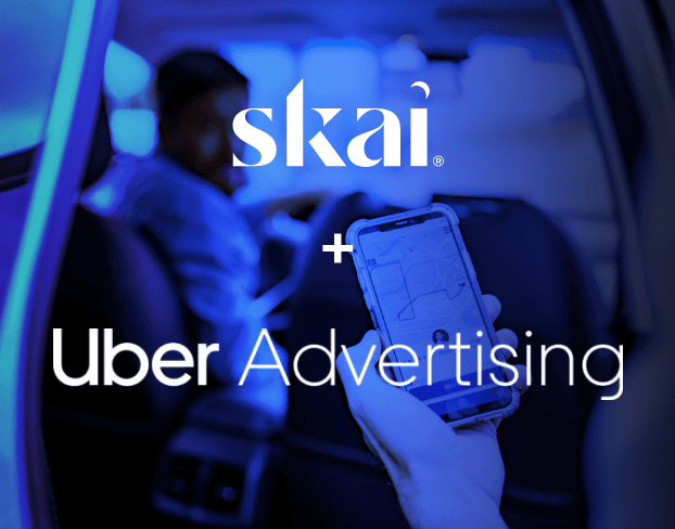Une personne tient un smartphone affichant une carte à l'intérieur d'une voiture. L'image présente les logos Skai, Skai Agent Connect et Uber Advertising, séparés par un signe « + ».